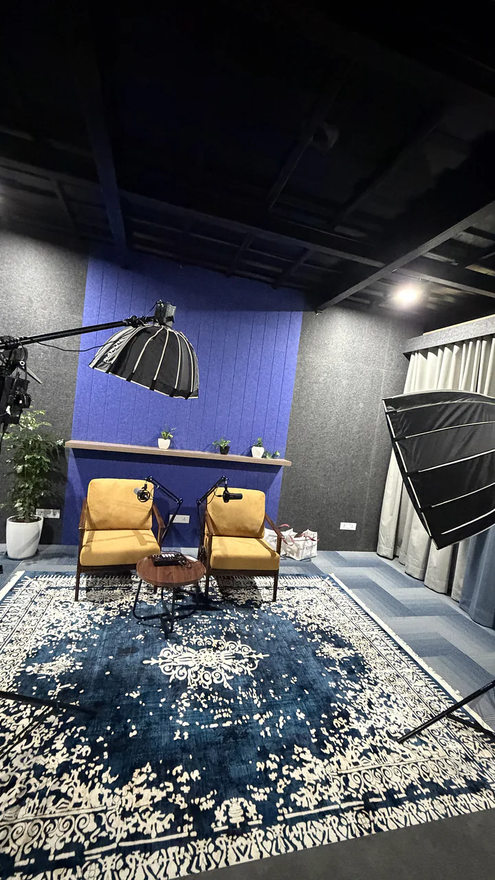 The CHQ podcast set: blue acoustic wall, two armchairs and a softbox