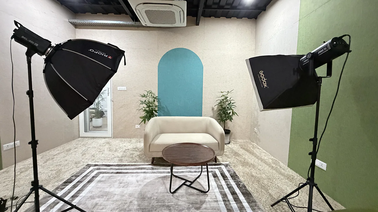 A lit studio set at CHQ with a sofa, softboxes and a teal arch